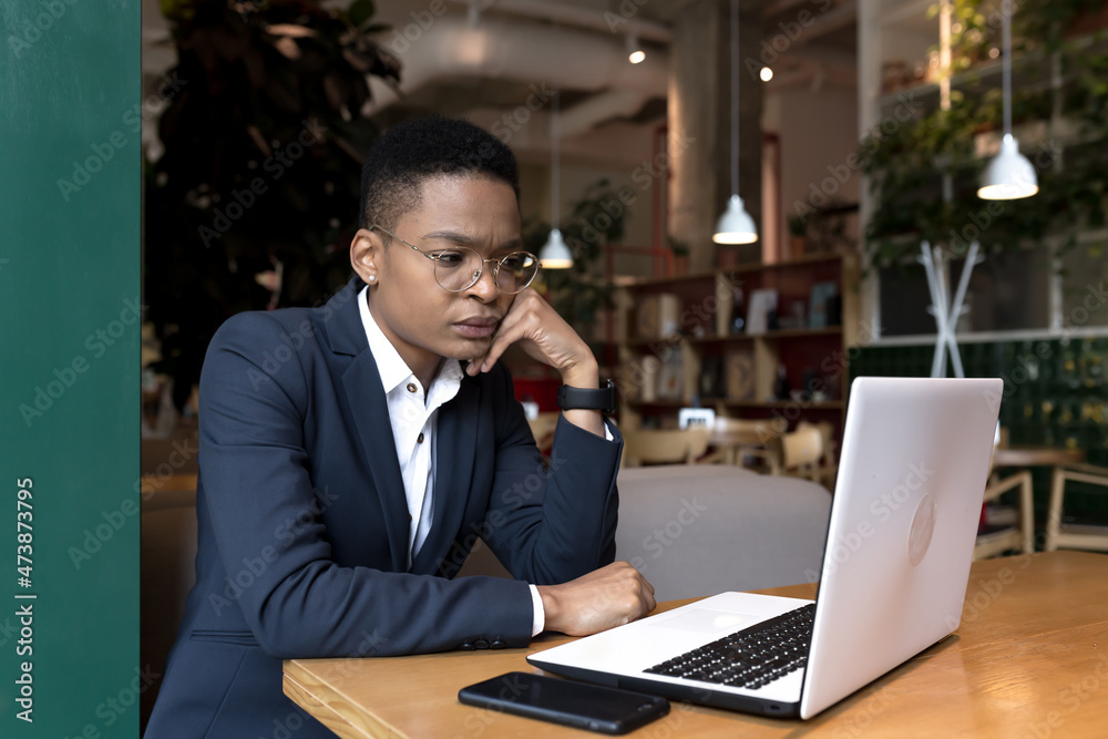 Young african american woman studying online sitting in cafe, using laptop remotely, pensive student Young african american woman studying online sitting in cafe, using laptop remotely, pensive student