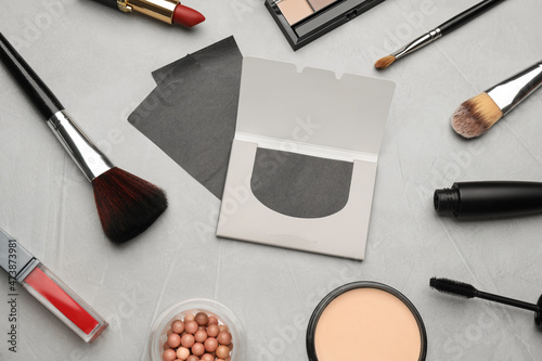 Facial oil blotting tissues and different decorative cosmetics on light grey background, flat lay. Mattifying wipes photo
