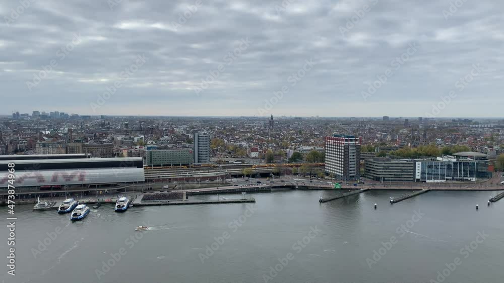 Trains depart and arrive at Amsterdam central train station. Passenger ferry arrives at dock terminal. View from famous A'dam Lookout tower. Amsterdam, North Holland, Netherlands Trains depart and arrive at Amsterdam central train station. Passenger ferry arrives at dock terminal. View from famous A'dam Lookout tower. Amsterdam, North Holland, Netherlands