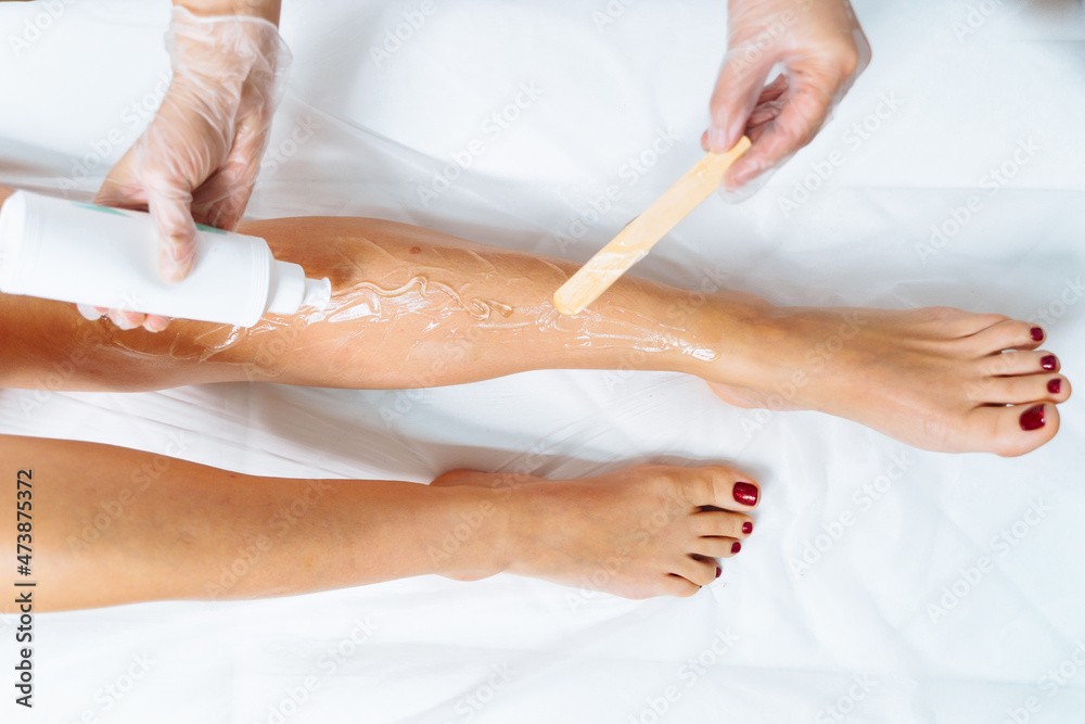 Laser epilation and cosmetology in beauty salon. Laser hair removal, skin care. Top view of woman legs during laser hair removal procedure. Applying conductive gel. Laser epilation and cosmetology in beauty salon. Laser hair removal, skin care. Top view of woman legs during laser hair removal procedure. Applying conductive gel.