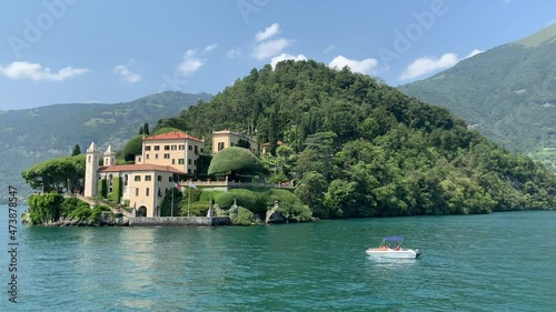 Landscape of Como Lake shore and Villa del Balbianello mansion house.  Moving boat in Como lake. Tremezzina, Como Lake, Lombardy, Italy.