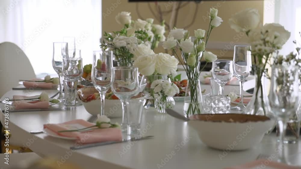 Served table in a restaurant for dinner, lunch or celebration. White tablecloth, plates, napkins and glasses, chairs. Holiday indoors. Empty with no people and food. Decorated with flowers for wedding Served table in a restaurant for dinner, lunch or celebration. White tablecloth, plates, napkins and glasses, chairs. Holiday indoors. Empty with no people and food. Decorated with flowers for wedding