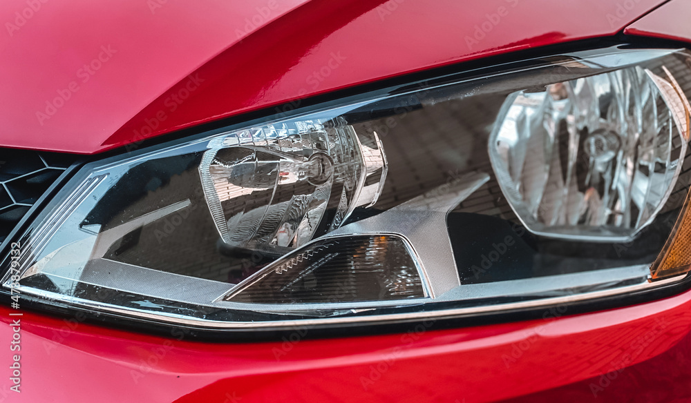 Close-up of halogen car headlights on a red car. Car details