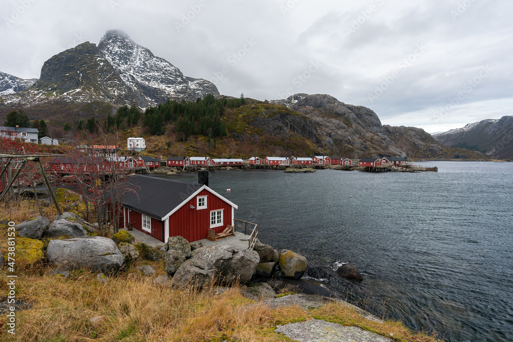 Nusfjord authentic fishing village with traditional red wooden hut houses in summer. Lofoten islands, Norway. Typical Rourbuer fishing cabins in cloudy weather. Nusfjord authentic fishing village with traditional red wooden hut houses in summer. Lofoten islands, Norway. Typical Rourbuer fishing cabins in cloudy weather.