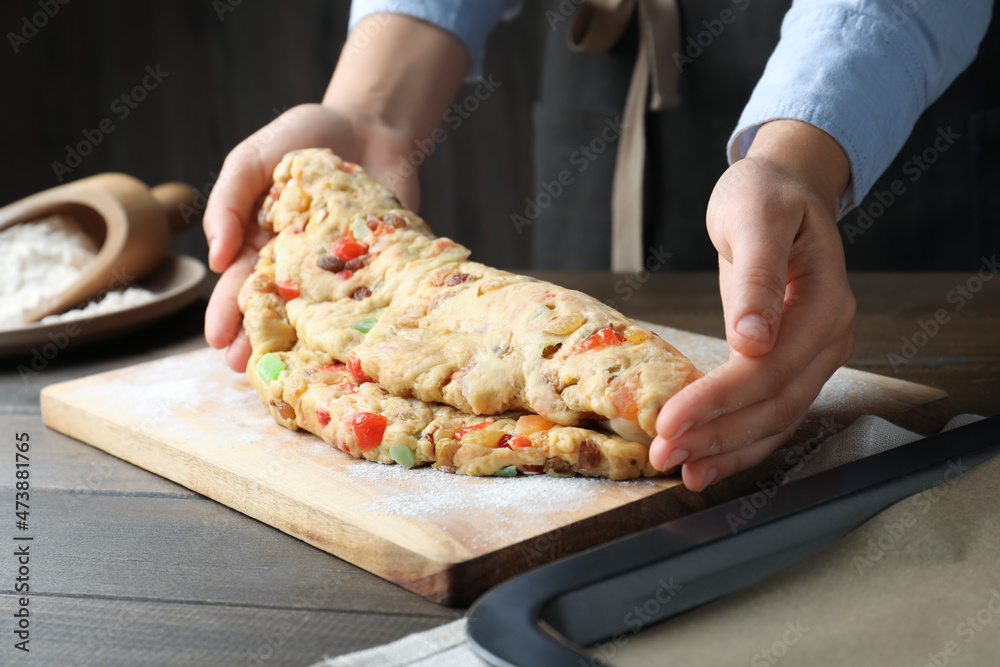 Woman making Stollen with candied fruits and raisins on wooden board at table, closeup