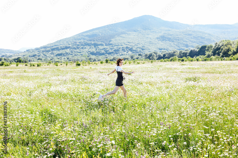 beautiful woman travels walking a field of daisies