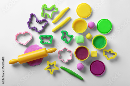Set of tools and color play dough on white background, top view