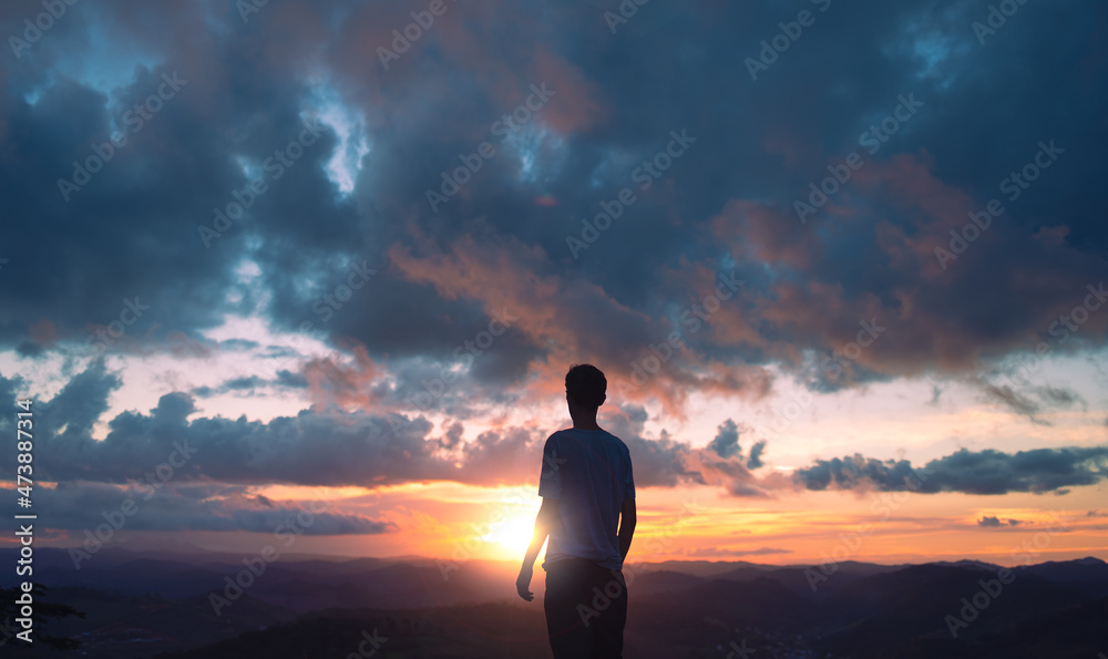 silhouette of a young man with the clouds and sunset in the background. silhouette of a young man with the clouds and sunset in the background.