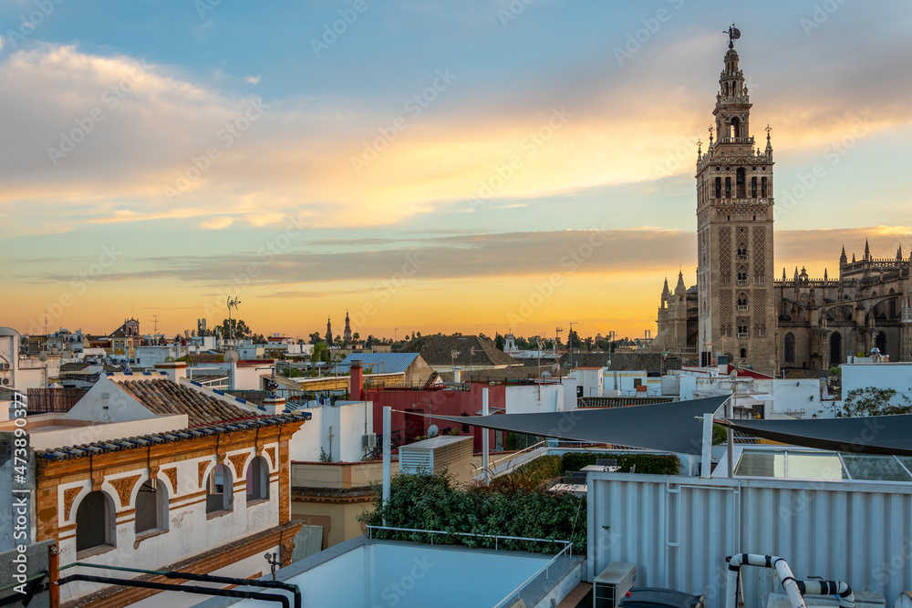 Fototapeta premium Sunset view from a rooftop overlooking the Andalusian city of Seville, Spain, with the Giralda Tower and the great Seville Cathedral in view over the skyline at early evening.