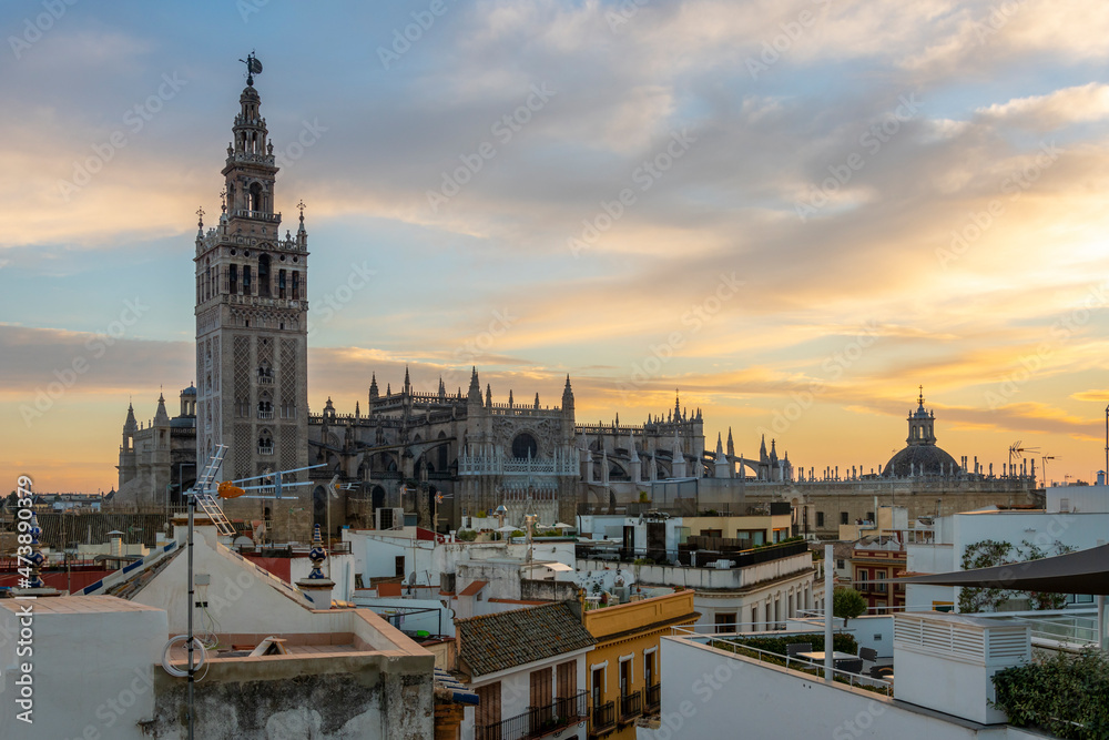 Sunset view from a rooftop overlooking the Andalusian city of Seville, Spain, with the Giralda Tower and the great Seville Cathedral in view over the skyline at early evening. Sunset view from a rooftop overlooking the Andalusian city of Seville, Spain, with the Giralda Tower and the great Seville Cathedral in view over the skyline at early evening.