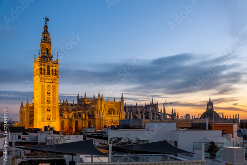 Sunset view from a rooftop overlooking the Andalusian city of Seville, Spain, with the Giralda Tower and the great Seville Cathedral in view over the skyline at early evening.