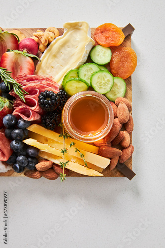 Cheese board with hummus, fruit and vegetables on a white background