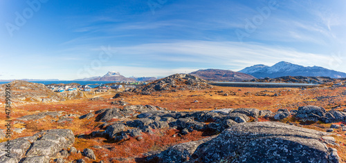 Autumn greenlandic  tundra with orange grass, stones, Inuit settlement and Sermitsiaq mountain in the background, Nuuk, Greenland photo