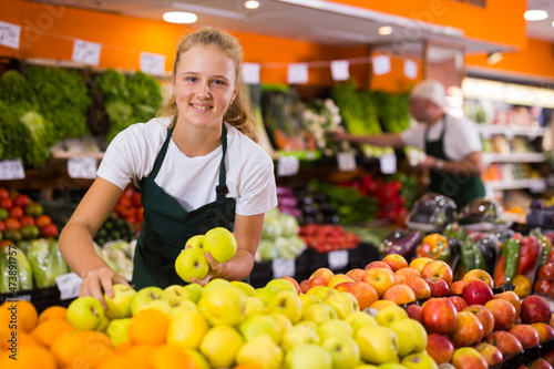 Fotografie Fifteen-year-old girl who works part-time in a store as a trainee saleswoman put