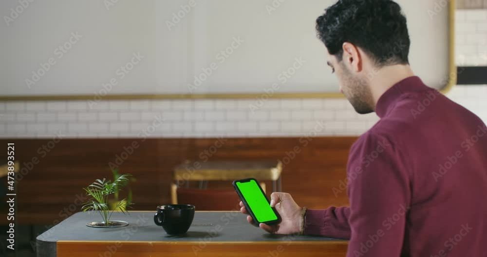 A man uses a phone with a green screen while sitting at a table A man uses a phone with a green screen while sitting at a table