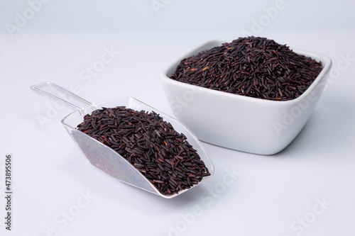riceberry rice in a white bowl and plastic spoon on white background
