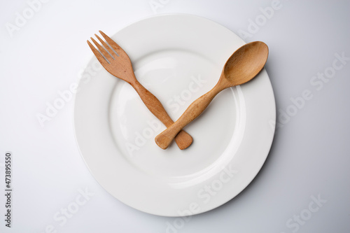clock white plate with wooden spoon and fork eating time meal concept