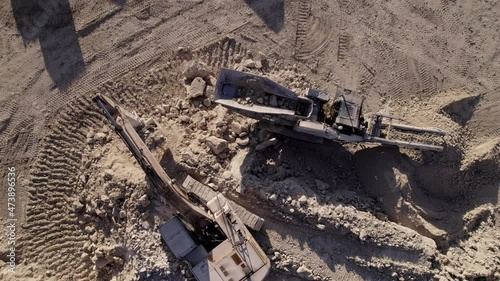 Drone aerial view of limestone quarry. Heavy machinery working for minerals extraction. Trucks, excavator, mobile portable crushing screening plant. Mining extractive industry