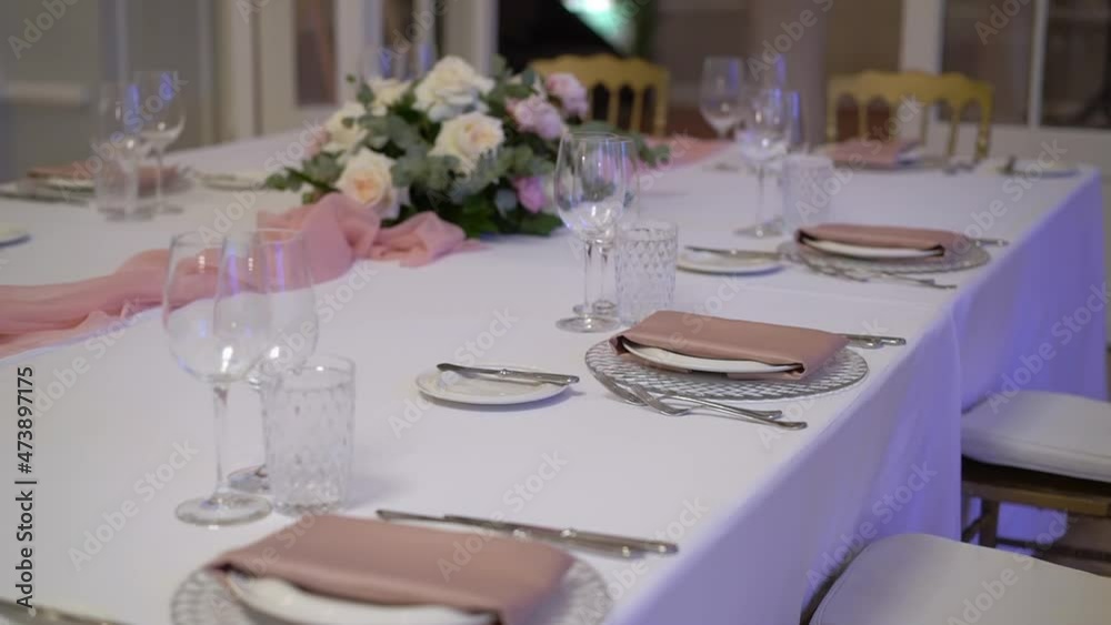 Served table in a restaurant for dinner, lunch or celebration. White tablecloth, plates, napkins and glasses, chairs. Holiday indoors. Empty with no people and food. Decorated with flowers for wedding Served table in a restaurant for dinner, lunch or celebration. White tablecloth, plates, napkins and glasses, chairs. Holiday indoors. Empty with no people and food. Decorated with flowers for wedding