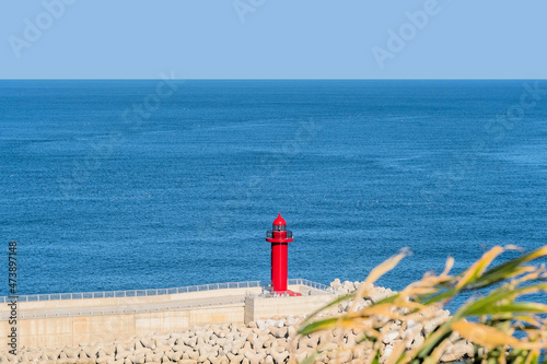 Red light house with ocean water in background.