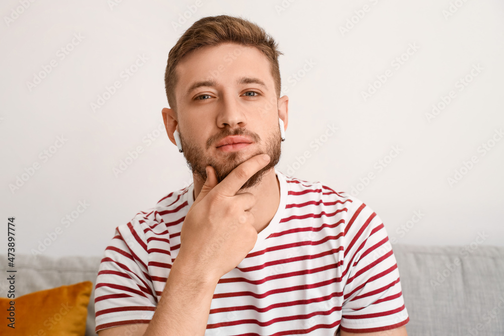 Thoughtful young man in earphones at home Thoughtful young man in earphones at home