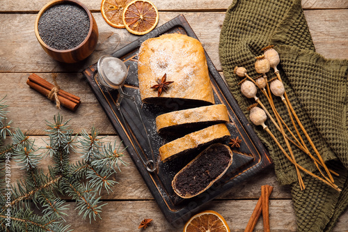 Obraz na płótnie Board with tasty poppy seed strudel and fir branch and ingredients on wooden bac