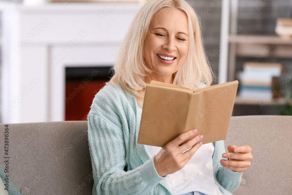 Beautiful mature woman reading book at home on autumn day Beautiful mature woman reading book at home on autumn day