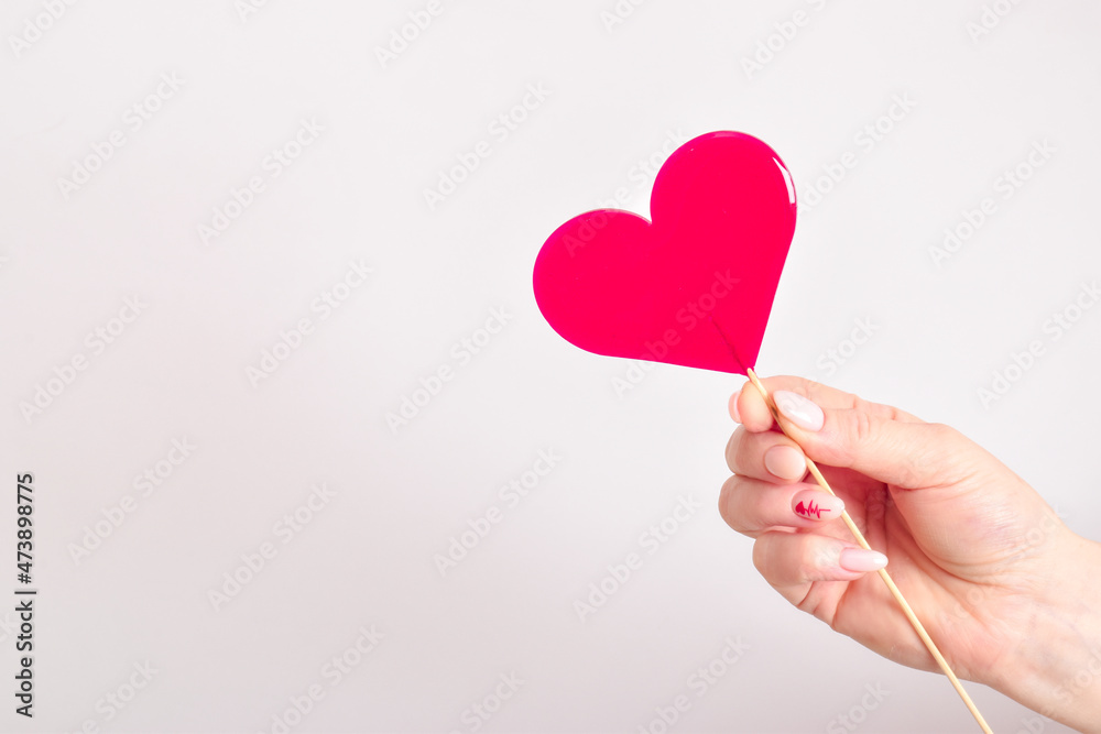 A heart-shaped lollipop in the hands of a girl. Valentine's day. A heart-shaped lollipop in the hands of a girl. Valentine's day.