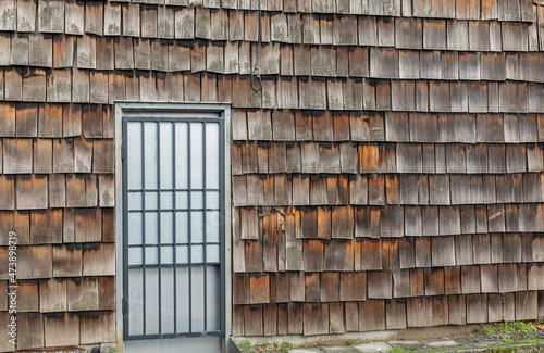 Details of an old house in country side. Rustic wall patterns of weathered cedar shake shingles with door.