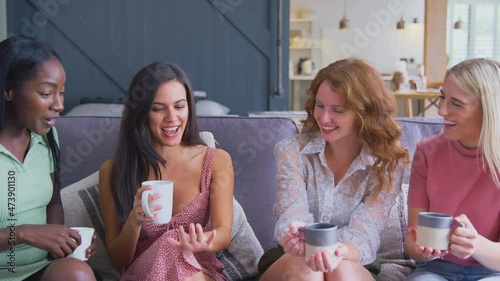 Multi-cultural group of women sitting on sofa at home admiring friends engagement ring - shot in slow motion