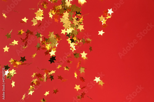 Flying confetti in shape of stars on red background
