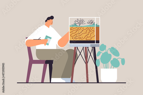 young man taking care of ant farm guy feeding ants in formicarium domestic insects concept