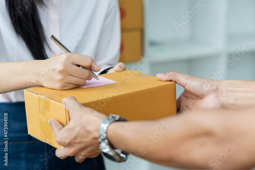 young woman hand writing address on sme business delivery concept box