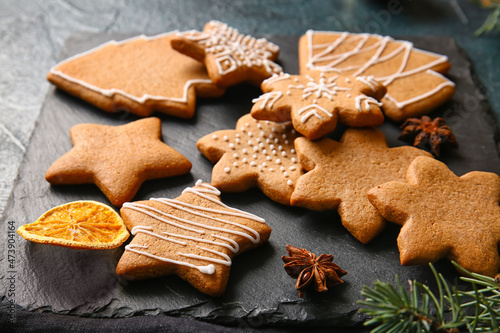 Board with sweet Christmas gingerbread cookies on black background