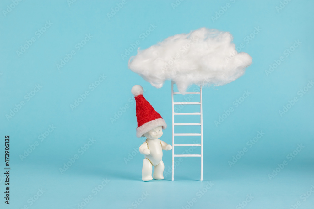 A figure of a baby in a hood near the stairs leading to the clouds. The trend of the New Year. Minimalism. A figure of a baby in a hood near the stairs leading to the clouds. The trend of the New Year. Minimalism.