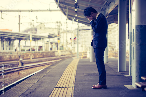 駅のホームで落ち込む男性　train