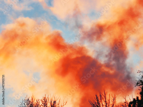 Dramatic orange and yellow smoke billowing into the sky from a forest