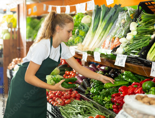 Fotografie Focused fifteen-year-old girl who works part-time in a store as a trainee salesw