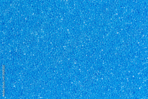Foam sponge porous texture background deep sky blue color. Extreme close-up view of unique detail abstract synthetic material. Horizontal composition for design, colored decoration backdrop.
