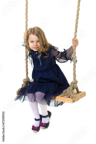 Lovely blonde little girl swinging on rope swing