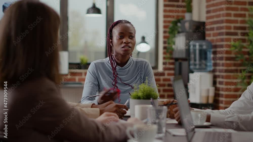 Close up of adult explaining marketing strategy to workmates in meeting boardroom. Woman talking about project planning and analysis to design presentation for business development. Close up of adult explaining marketing strategy to workmates in meeting boardroom. Woman talking about project planning and analysis to design presentation for business development.