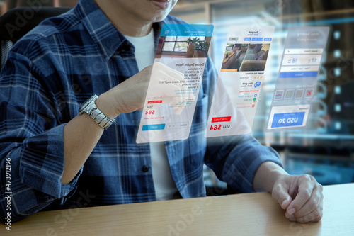 Man in casual cloth interacting with futuristic virtual screen of hotel reservation and travel planning application