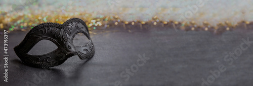 Carnival Venetian black mask on dark grey color background, female disguise, masquerade