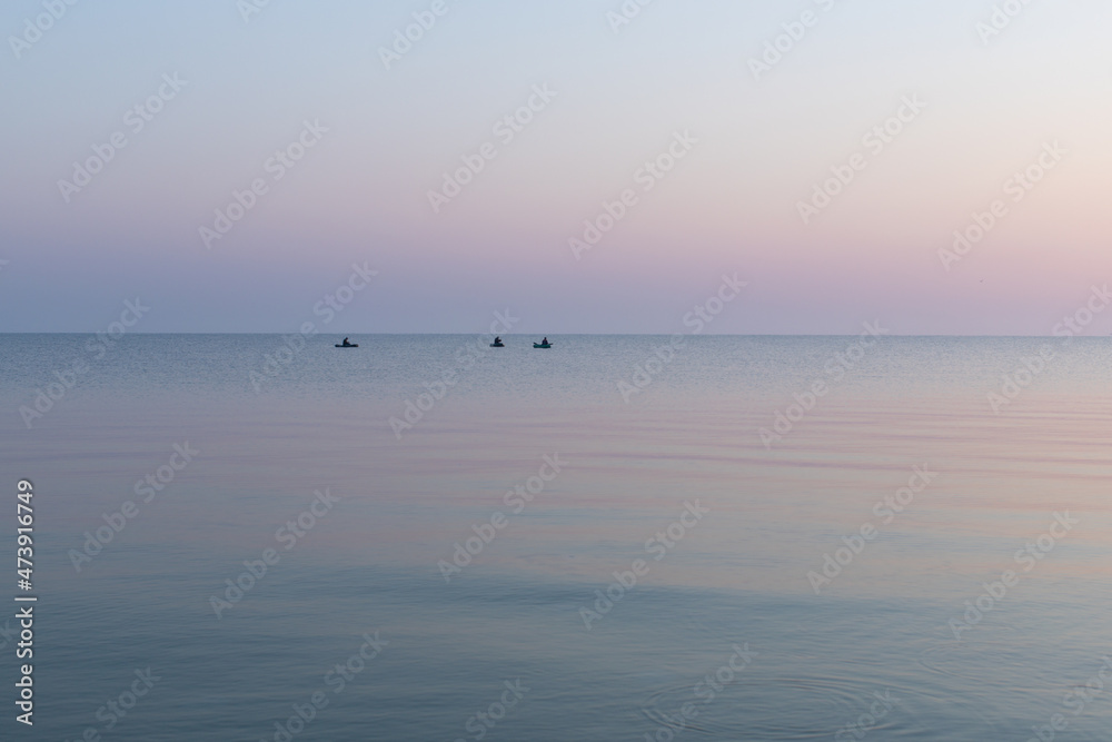 Sea at dawn with three fishing rubber boats, calm, Sea of Azov, Russia.