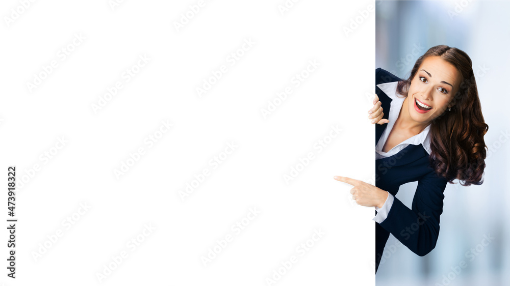 Happy excited woman in black suit showing pointing mock up white banner signboard. Business and advertising concept. Copy space empty place. Blurred modern office background.. Happy excited woman in black suit showing pointing mock up white banner signboard. Business and advertising concept. Copy space empty place. Blurred modern office background..