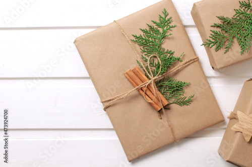 Gift boxes wrapped in craft paper with cinnamon stick on white background. New Year presents holiday preparations DIY.
