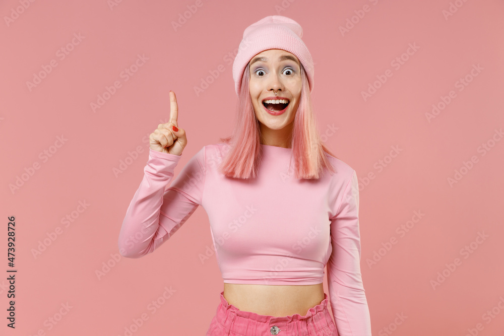 Young woman 20s with bright dyed rose hair wear rosy top shirt hat holding index finger up with great new idea isolated on plain light pastel pink background studio People lifestyle fashion concept Young woman 20s with bright dyed rose hair wear rosy top shirt hat holding index finger up with great new idea isolated on plain light pastel pink background studio People lifestyle fashion concept
