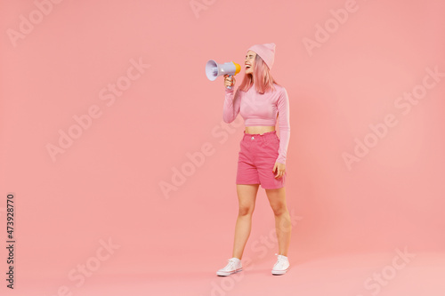 Full body young woman 20s with bright dyed rose hair in rosy top shirt hat hold scream in megaphone announces discounts sale Hurry up isolated on plain light pastel pink background studio portrait