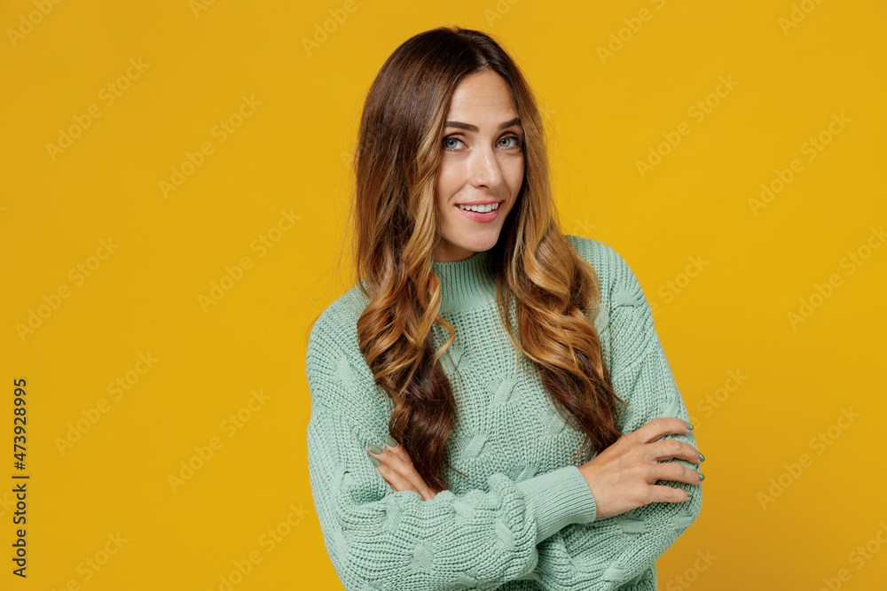 Young smiling happy fun cheerful caucasian woman 30s in green knitted sweater hold hands crossed folded look camera isolated on plain yellow color background studio portrait. People lifestyle concept. Young smiling happy fun cheerful caucasian woman 30s in green knitted sweater hold hands crossed folded look camera isolated on plain yellow color background studio portrait. People lifestyle concept.