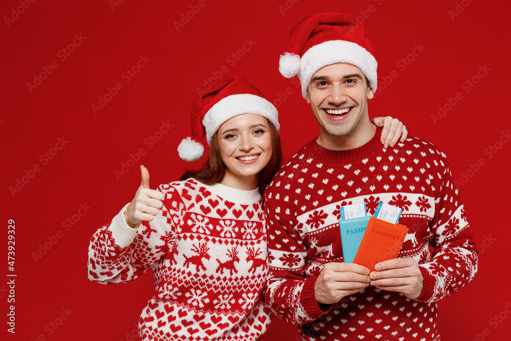 Traveler tourist couple friends woman man wear winter clothes hat hold ticket passport show thumbup isolated on plain red background Passenger travel abroad weekend getaway Air flight journey concept Traveler tourist couple friends woman man wear winter clothes hat hold ticket passport show thumbup isolated on plain red background Passenger travel abroad weekend getaway Air flight journey concept